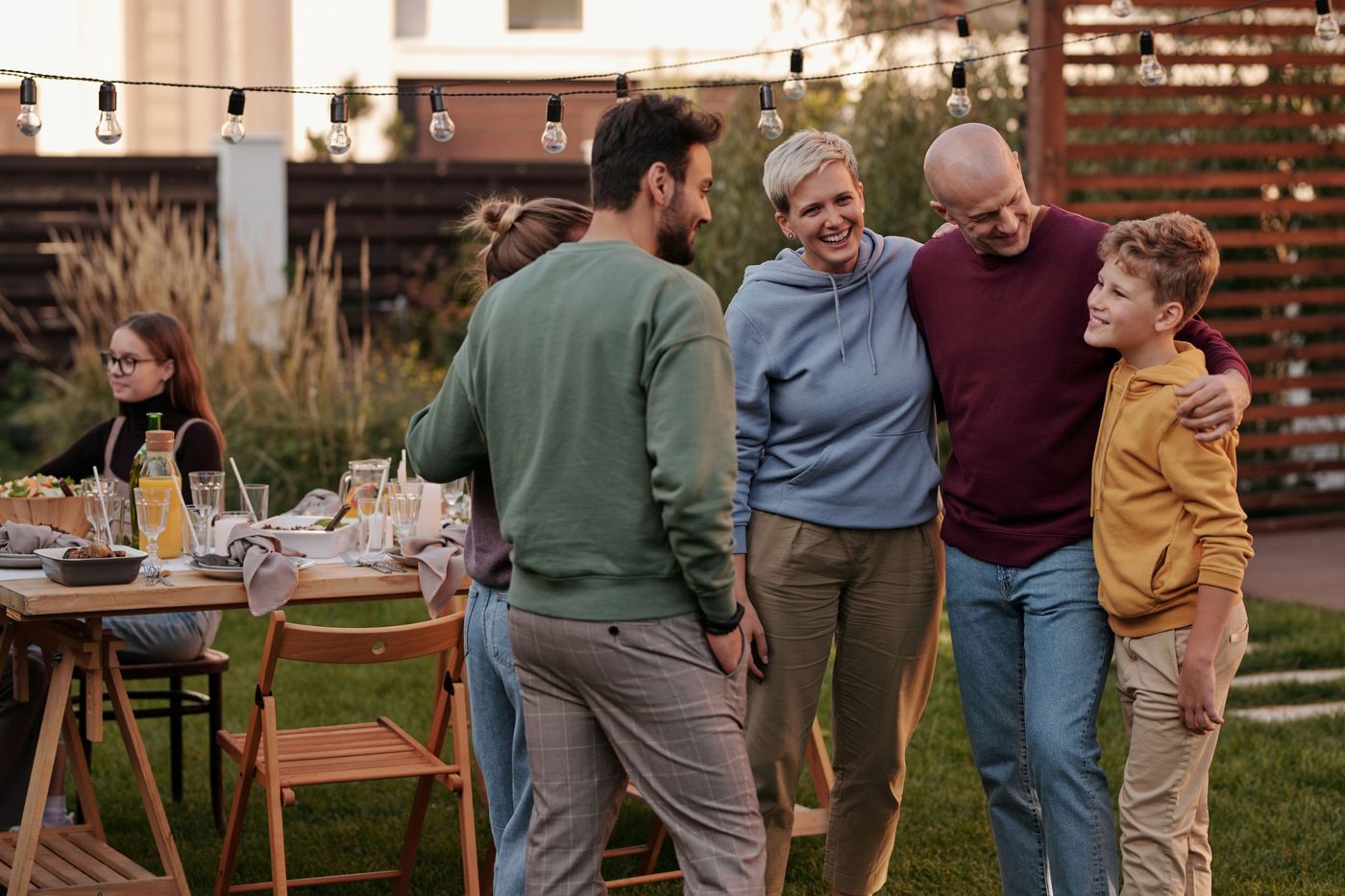 Family and friends gathering outdoors under string lights at a garden party