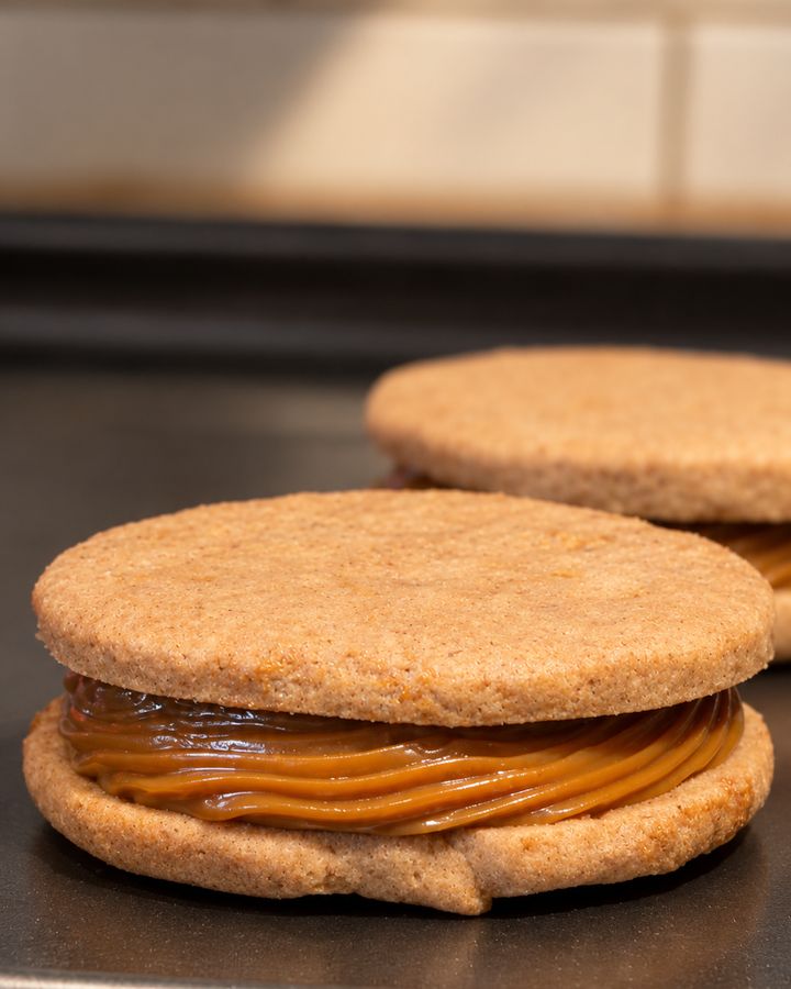 A freshly filled alfajor with a thick layer of dulce de leche, before its chocolate coating