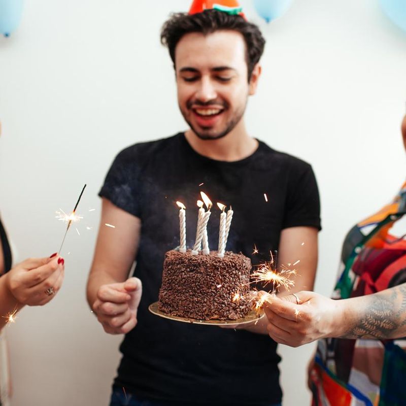 Friends celebrating a birthday with a chocolate cake and sparklers