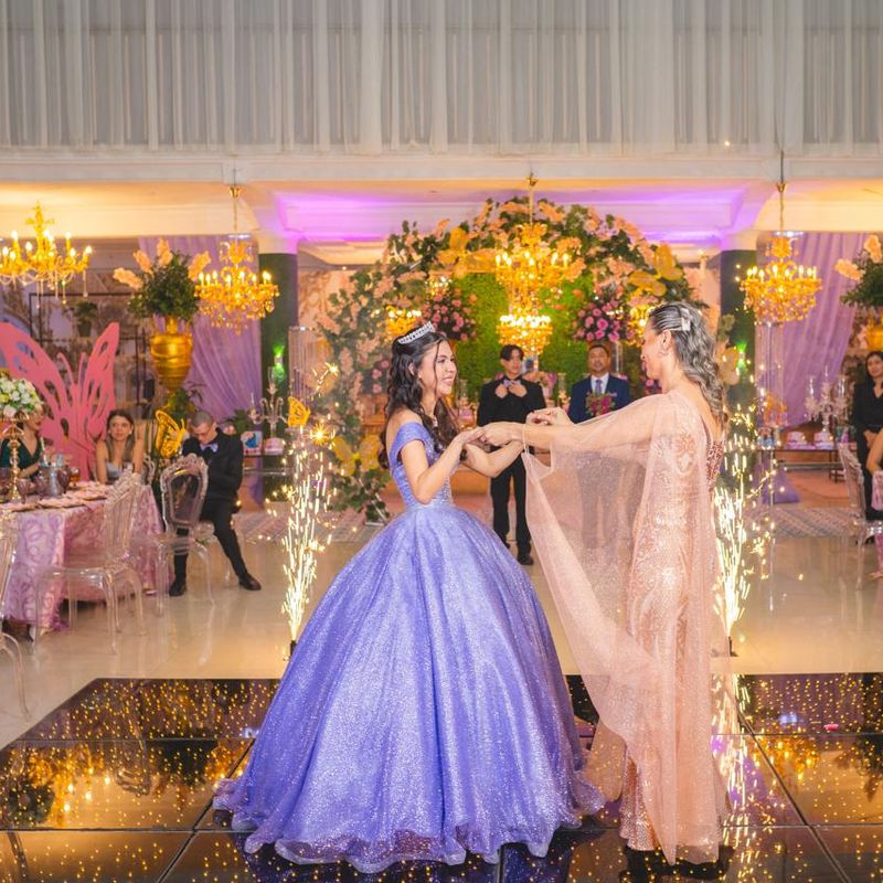 Quinceañera in a lavender gown dancing in a decorated ballroom