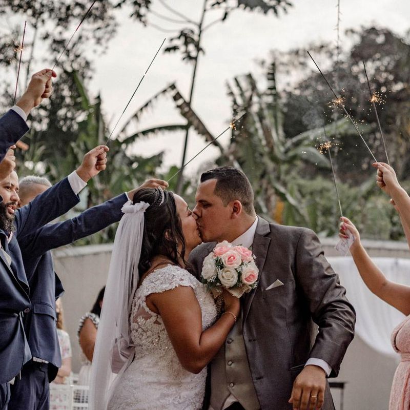 Newlyweds kissing while guests hold sparklers